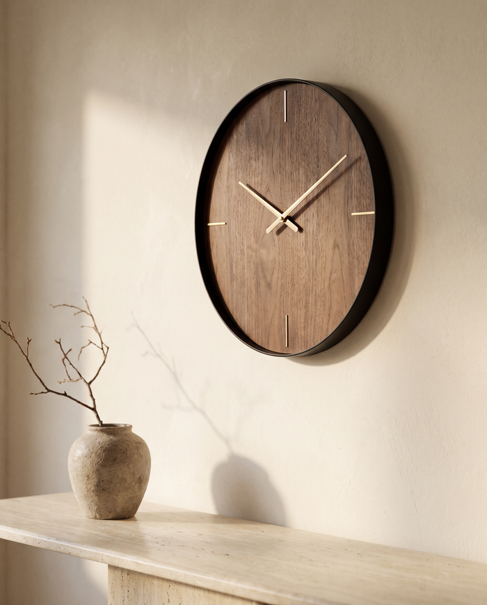 Sculptural walnut and brass minimalist wall clock on a warm ivory plaster wall